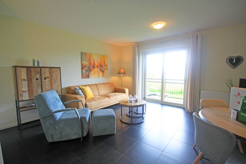 Lichte woonkamer van Appartement Bos en Duin 42, De Dennen, Texel met uitzicht op het groene landschap.