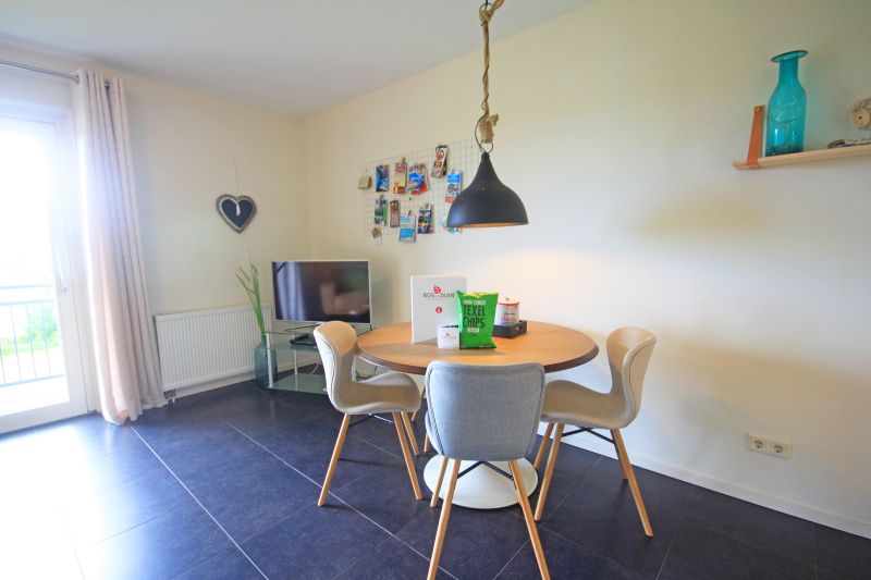 Eetgedeelte in Appartement Bos en Duin 42, Texel met ronde tafel en moderne stoelen voor gezellige maaltijden.