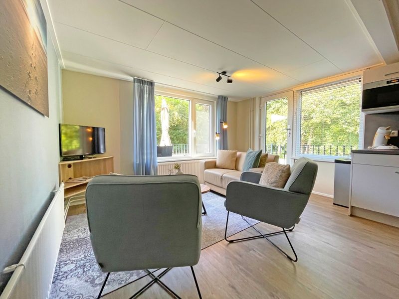 Dining area in Apartment Bos en Duin 22, De Dennen, Texel with wooden table and stylish chairs.