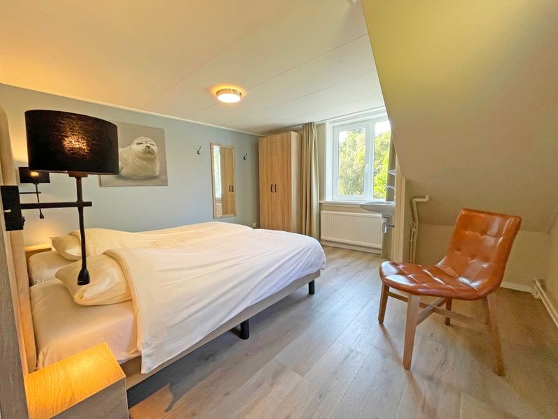 Second bedroom in Apartment Bos en Duin 22, De Dennen, Texel with warm furnishings and closet space.