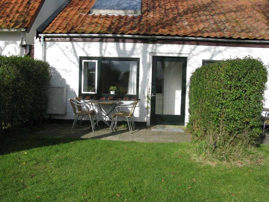 Veranda des Ferienhauses Duumpie in De Dennen, Texel mit Sitzgelegenheiten und gruener Umgebung.