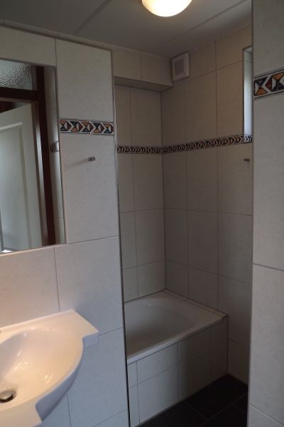 Stijlvolle badkamer in Vakantiehuis Gortersmient 216, De Dennen, Texel met bad en moderne tegels.