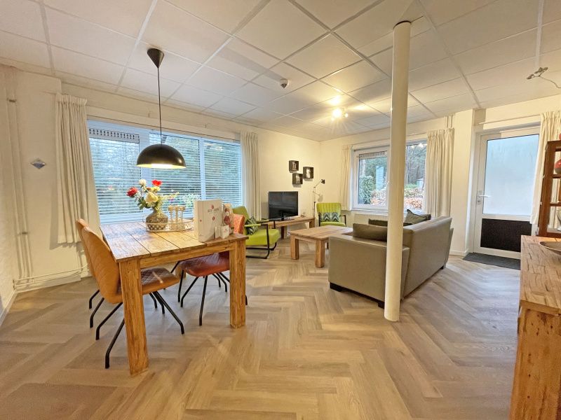 Bright and spacious dining room in Apartment Bos en Duin 04, De Dennen, Texel with wooden table and modern chairs.