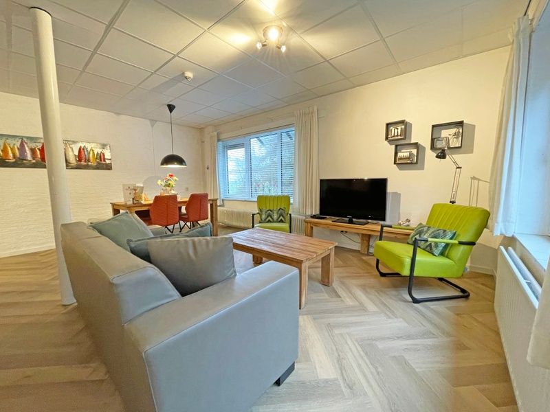 Stylish sitting area in Apartment Bos en Duin 04, De Dennen, Texel with flat-screen TV and colorful accents.