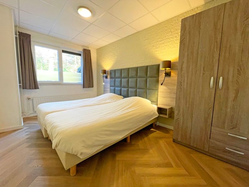 Spacious bedroom in Apartment Bos en Duin 04, De Dennen, Texel with soft lighting and large closet.