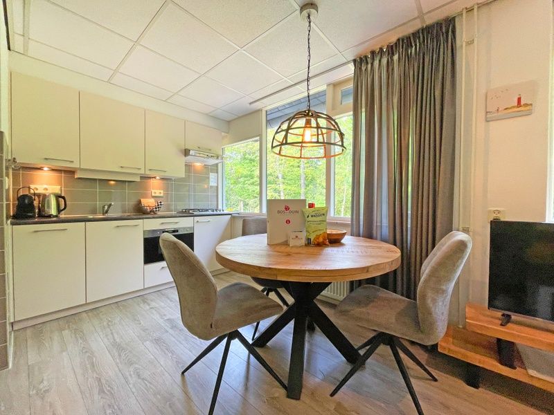 Essecke mit moderner Kueche im Appartement Bos en Duin 23, Texel, umgeben von Natur.
