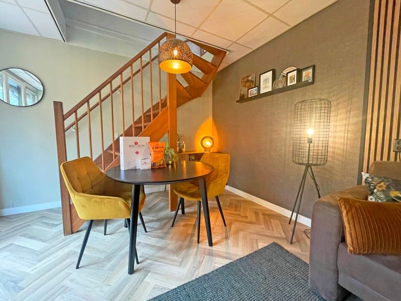 Essbereich im Appartement Bos en Duin 24, De Dennen, Texel mit Holztreppe und gemuetlicher Beleuchtung fuer stimmungsvolles Essen.