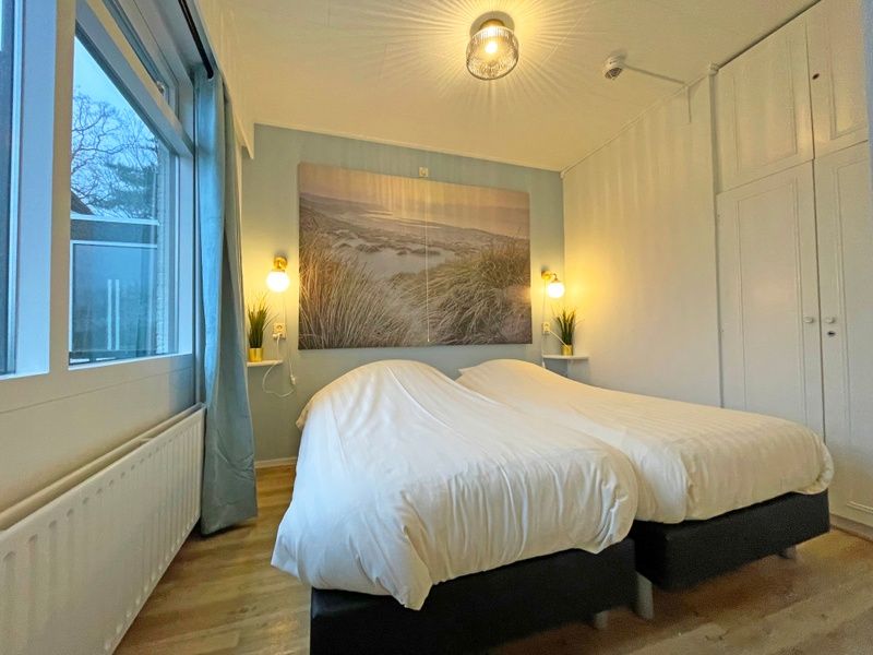 Second bedroom in Apartment Bos en Duin 27, De Dennen, Texel with two single beds and fresh furnishings.