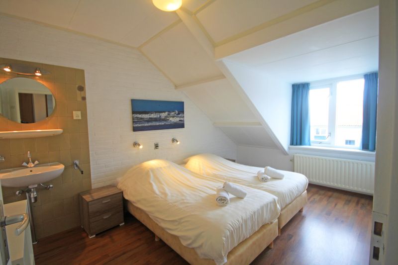 Attractive bedroom with two beds in Apartment Bos en Duin 33, De Dennen, Texel for a good night's sleep.