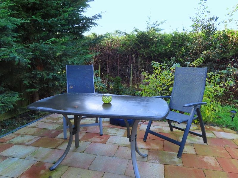 Ruhige Terrasse des Ferienhauses Dunkonijn, De Dennen, Texel, umgeben von gruener Natur.