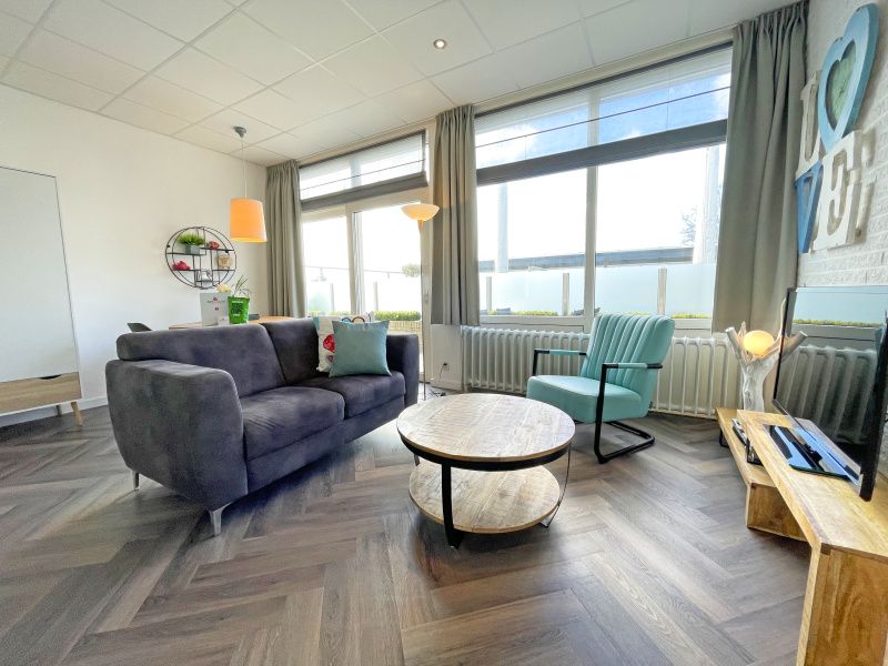 Bright living room of Apartment Bos en Duin 02, Texel, with large windows and an inviting seating area.