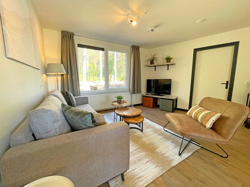 Helles Wohnzimmer des Apartments Bos en Duin 09, De Dennen, Texel mit grossen Fenstern und moderner Einrichtung.