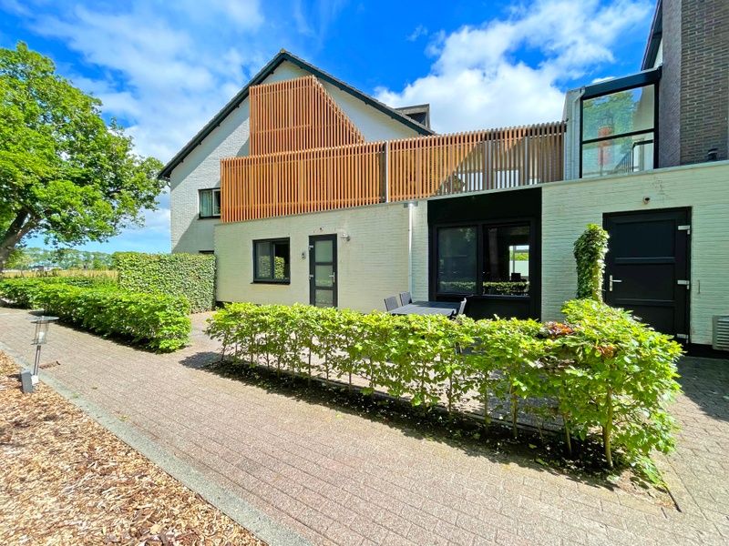 Aussenansicht des Appartements Bos en Duin 09, De Dennen, Texel mit Terrasse und gruener Umgebung.
