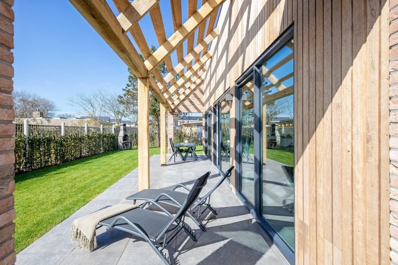 Ontspannen op het terras van Bungalowpark 't Luwe Land - Nieuw Vredelust, Texel. Comfortabele ligstoelen en natuurlijke omgeving.