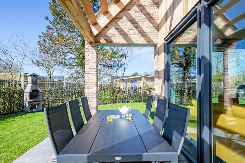 Bungalowpark 't Luwe Land - Nieuw Vredelust, De Dennen, Texel. Gezellige eethoek op het terras met uitzicht op de groene tuin.