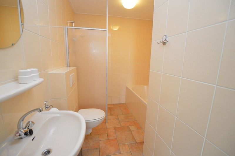 Modern bathroom in Bungalow Uterste Coogh 98, De Dennen, Texel with shower and bathtub.