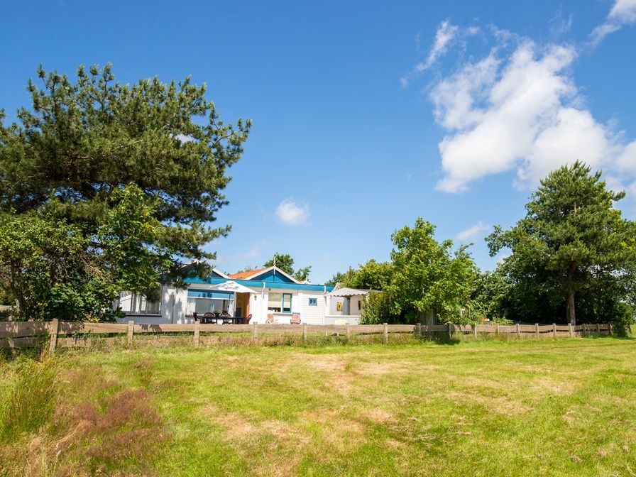 Meadow View vacation home in De Dennen, Texel with surrounding nature and blue sky.