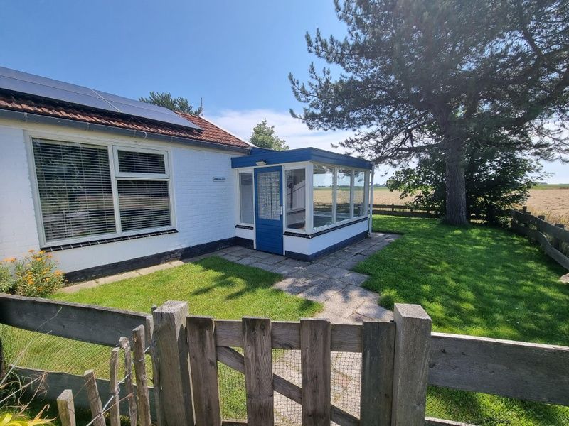 Entrance of Weidezicht vacation home in De Dennen, Texel with garden and green surroundings.