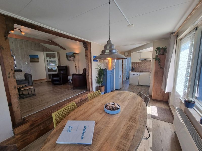 Dining room of Weidezicht vacation home in De Dennen, Texel with wooden table and view.