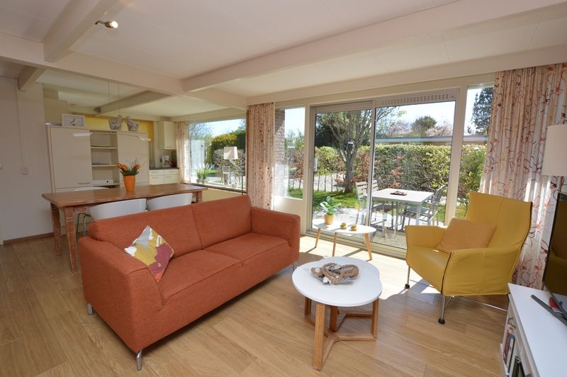Offenes Wohnzimmer und Kueche im Bungalow Verste Coogh 64, De Dennen, Texel mit Blick auf die Terrasse.