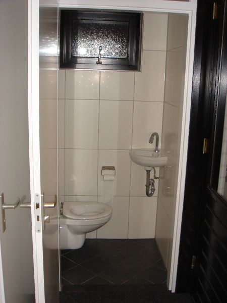 Kompakte Toilette im Ferienhaus Gortersmient 354 mit gefliestem Boden und Fenster in De Dennen Texel.