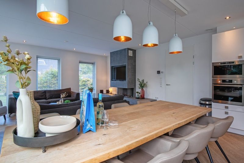 Moderne Essecke im Bungalowpark 't Hoogelandt - Villa Bloem en Bos, Texel mit gemuetlicher Beleuchtung und Holztisch.