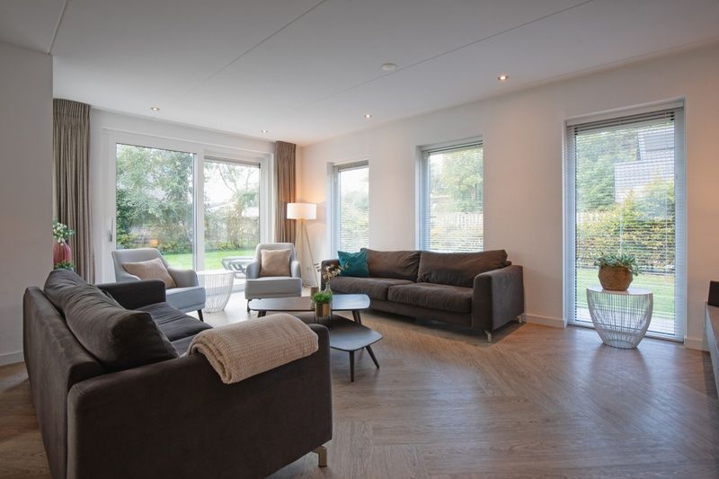 Helles und geraeumiges Wohnzimmer der Villa Bloem en Bos in De Dennen, Texel, mit grossen Fenstern und bequemen Sitzgelegenheiten.