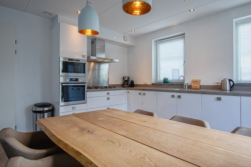 Voll ausgestattete Kueche in der Villa Bloem en Bos, De Dennen, Texel mit modernen Geraeten und Esstisch aus Holz.