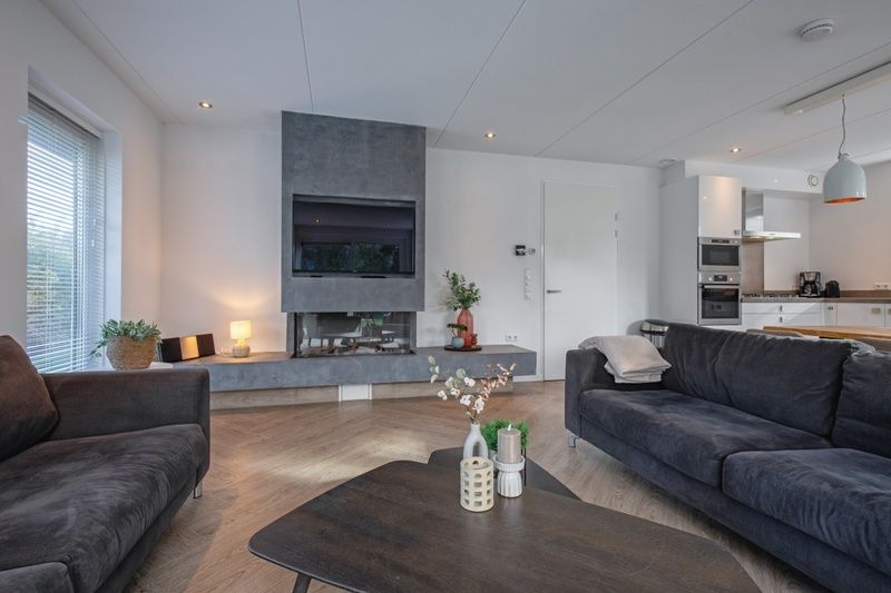 Stilvolles und modernes Wohnzimmer im Bungalowpark 't Hoogelandt - Villa Bloem en Bos, Texel mit Kamin und dekorativen Elementen.