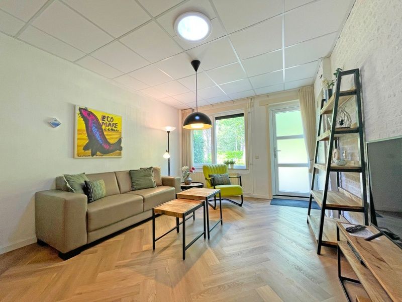 Lichte woonkamer van Appartement Bos en Duin 05, De Dennen, Texel met uitzicht op de groene omgeving.