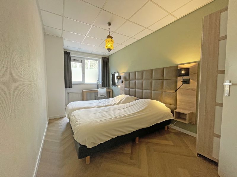 Comfortabele slaapkamer in Appartement Bos en Duin 05, De Dennen, Texel met twee eenpersoonsbedden en sfeervolle verlichting.