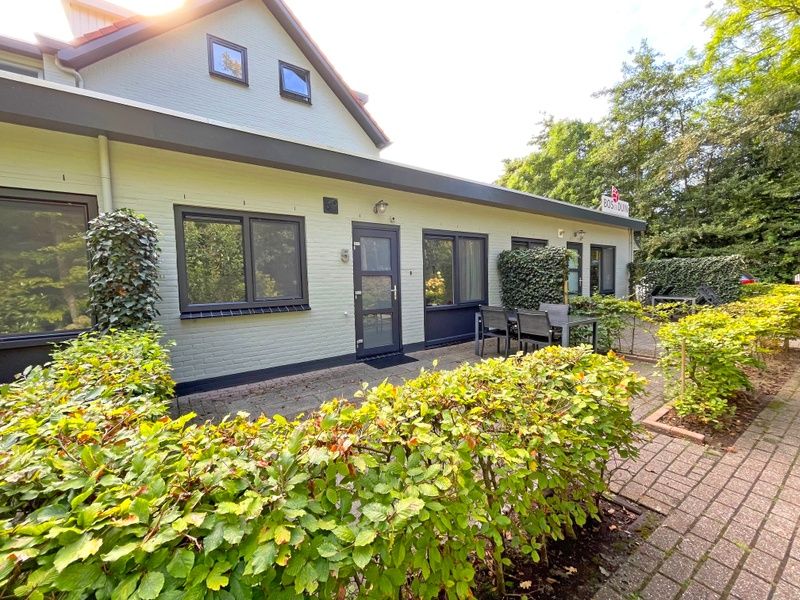 Buitenterras van Appartement Bos en Duin 05, De Dennen, Texel met zitgelegenheid en groene omheining.