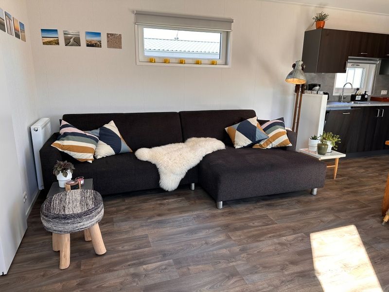 Spacious sitting area in Holiday Park de Bremakker - Bosveld 141, Texel with modern decoration and wooden floor.