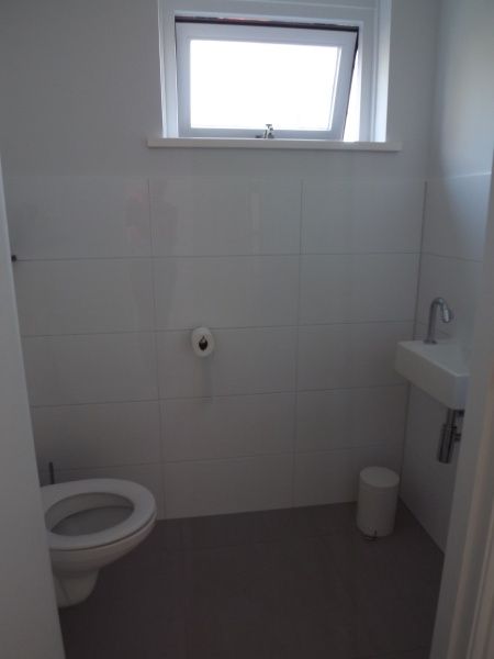 Compact toilet in Vakantiehuis Gortersmient 320, De Dennen, Texel met strak design en natuurlijk licht, ideaal voor comfort.