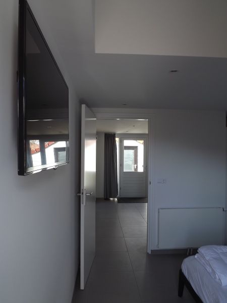 Moderne slaapkamer in Vakantiehuis Gortersmient 320, De Dennen, Texel met flatscreen tv, comfortabele bedden en serene sfeer.