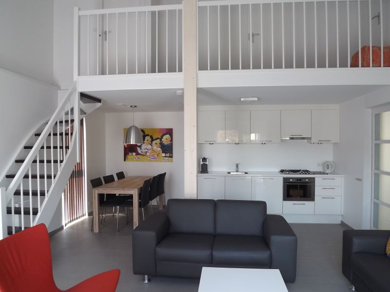 Stijlvolle woonkamer in Vakantiehuis Gortersmient 320, De Dennen, Texel met open keuken en eethoek, ideaal voor familiebijeenkomsten.