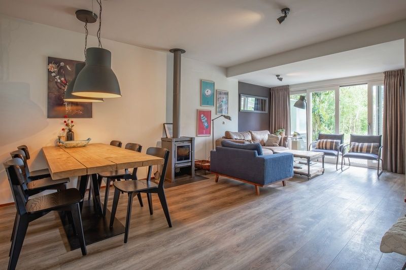 Ruime eet- en zithoek in Bungalowpark Gortersmient - Blommenzee, De Dennen, Texel met uitzicht op tuin.