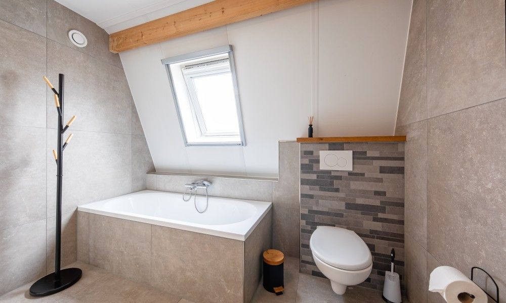 Luxurioeses Badezimmer in Wulpenweid 10 de Wulp, Ferienhaus De Dennen Texel mit Badewanne und Toilette.
