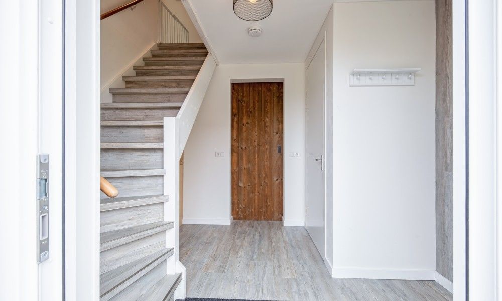 Eingangshalle von Wulpenweid 10 de Wulp, Ferienhaus De Dennen Texel mit Holztreppe und Garderobe.