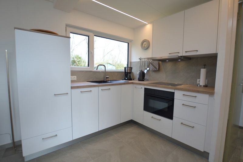 Modern kitchen in Tempelierweg 38, vacation home in De Dennen, Texel with sleek white cabinets.