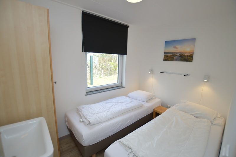 Bedroom with two beds in Tempelierweg 38, vacation home in De Dennen, Texel for a comfortable night's sleep.