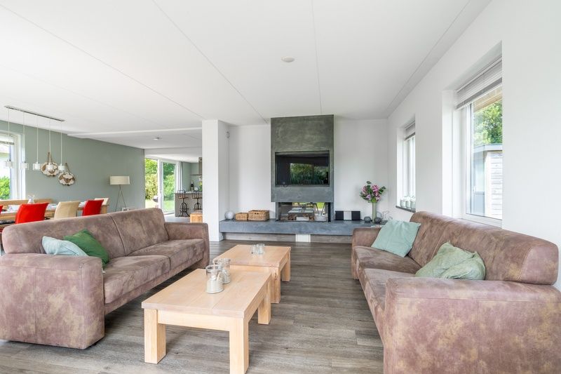 Geraeumiges Wohnzimmer in der Villa 106F, Bungalowpark 't Hoogelandt, Texel, mit modernem Mobiliar und Kamin.