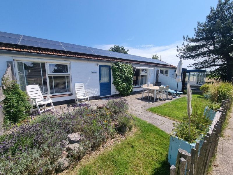 Zonnig terras bij Boszicht vakantiehuis in De Dennen, Texel met comfortabele stoelen.