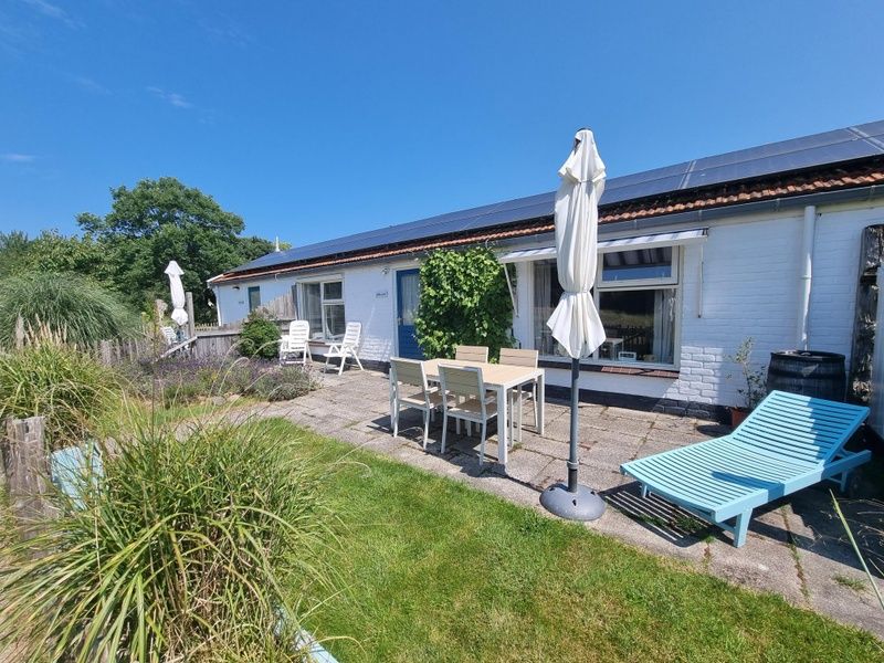 Ruim terras van Boszicht in De Dennen, Texel met ligstoelen en parasol.