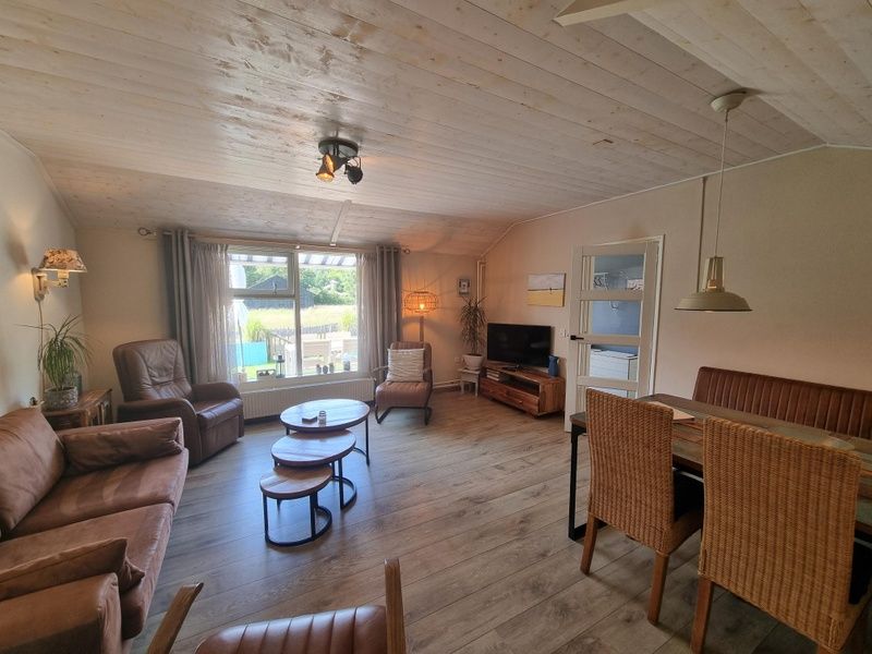 Lichte woonkamer van Boszicht vakantiehuis in De Dennen, Texel met uitzicht op tuin.