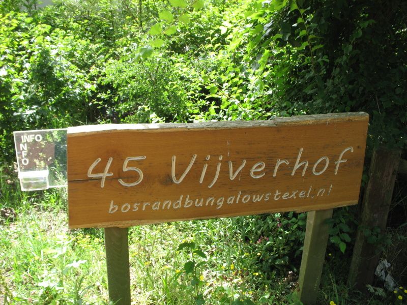 Information board of Vijverhof vacation home in De Dennen, Texel surrounded by greenery.