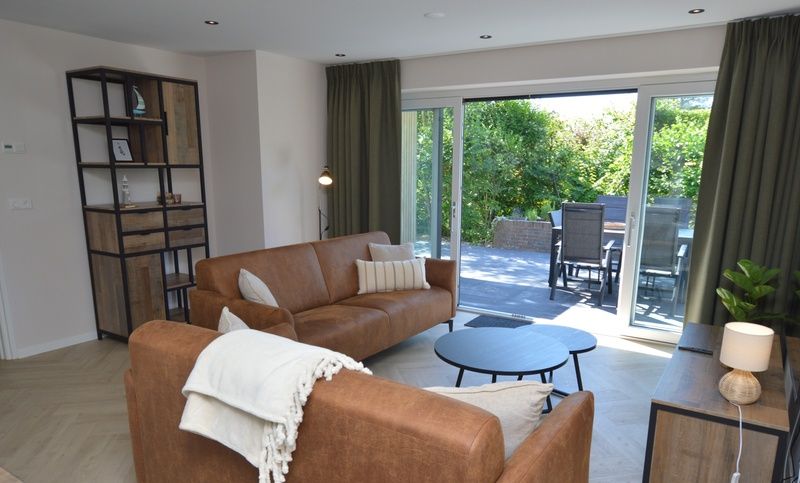 Modernes Wohnzimmer mit Zugang zur Terrasse im Bungalow 't Hoogelandt 58, De Dennen Texel.