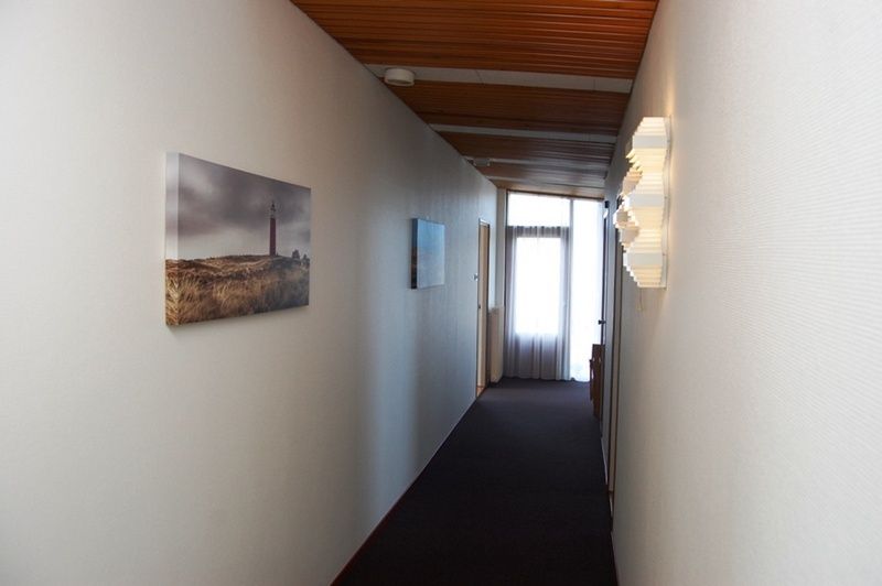Langer Korridor im Ferienhaus Lelie, Texel, mit Kunstwerken und moderner Beleuchtung.