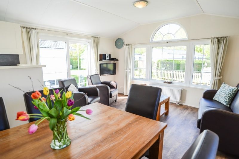 Dining area with flowers in Holiday Park De Koorn-aar Type F, De Dennen, Texel, overlooking nature.