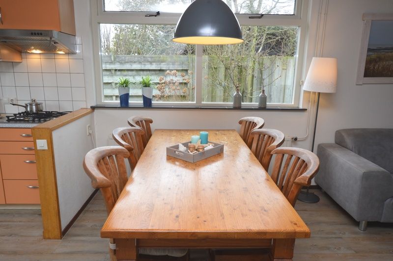 Essecke im Ferienhaus Iris, De Dennen, Texel mit Holztisch und Stuehlen.
